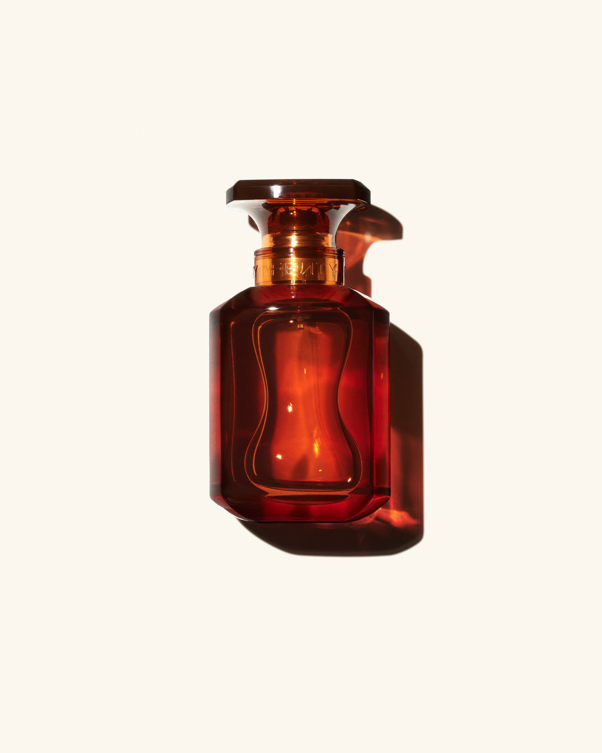 Fenty Eau de Parfum clear chestnut brown tinted glass perfume bottle on beige background