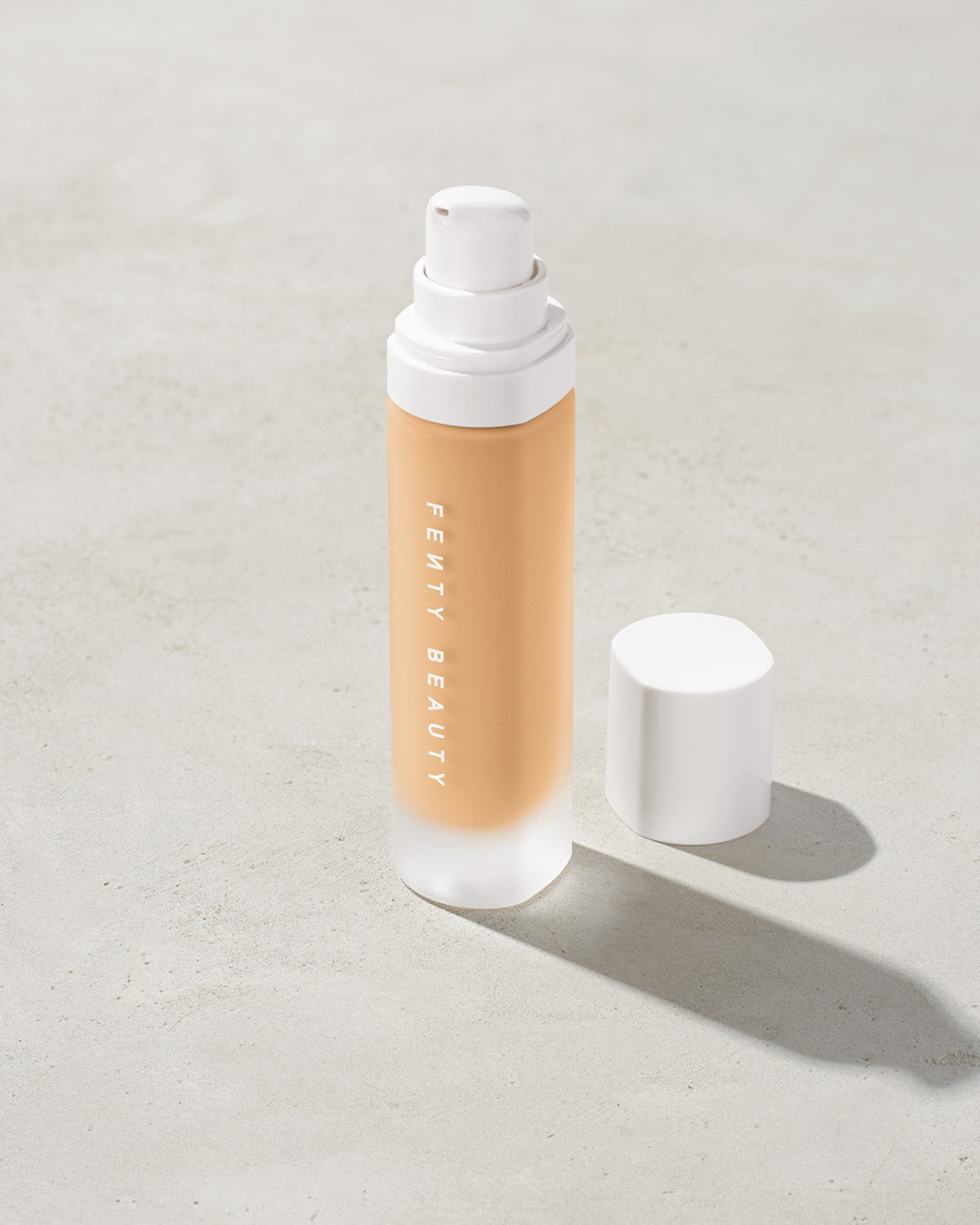 open bottle of Fenty Beauty Pro Filt'r Soft Matte Longwear Foundation with pump dispenser in shade #190 on concrete background