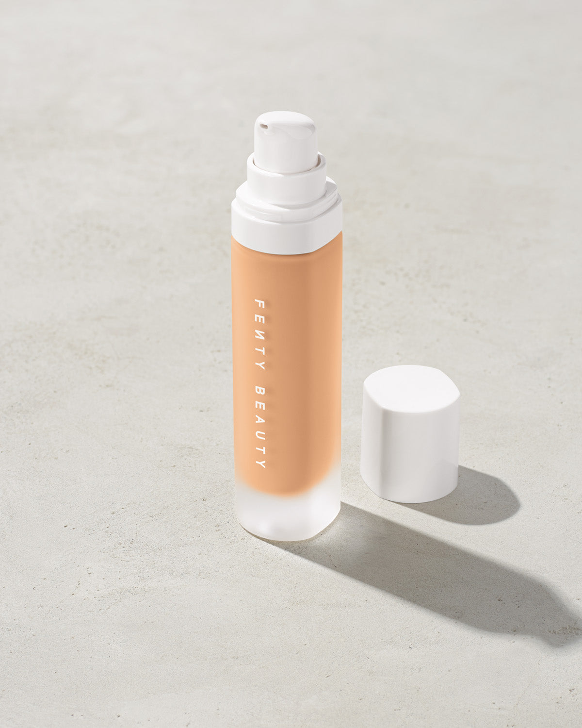 open bottle of Fenty Beauty Pro Filt'r Soft Matte Longwear Foundation with pump dispenser in shade #230 on concrete background