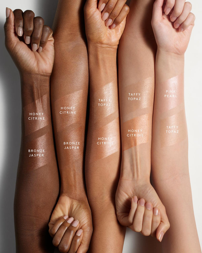 Eaze Drop’Lit All-Over Glow Enhancer swatches in all available shades shown on arms with light, medium, and deep skin tones.