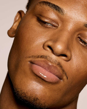 deep skin toned model wearing gloss bomb universal lip luminizer in shade Glass Slipper