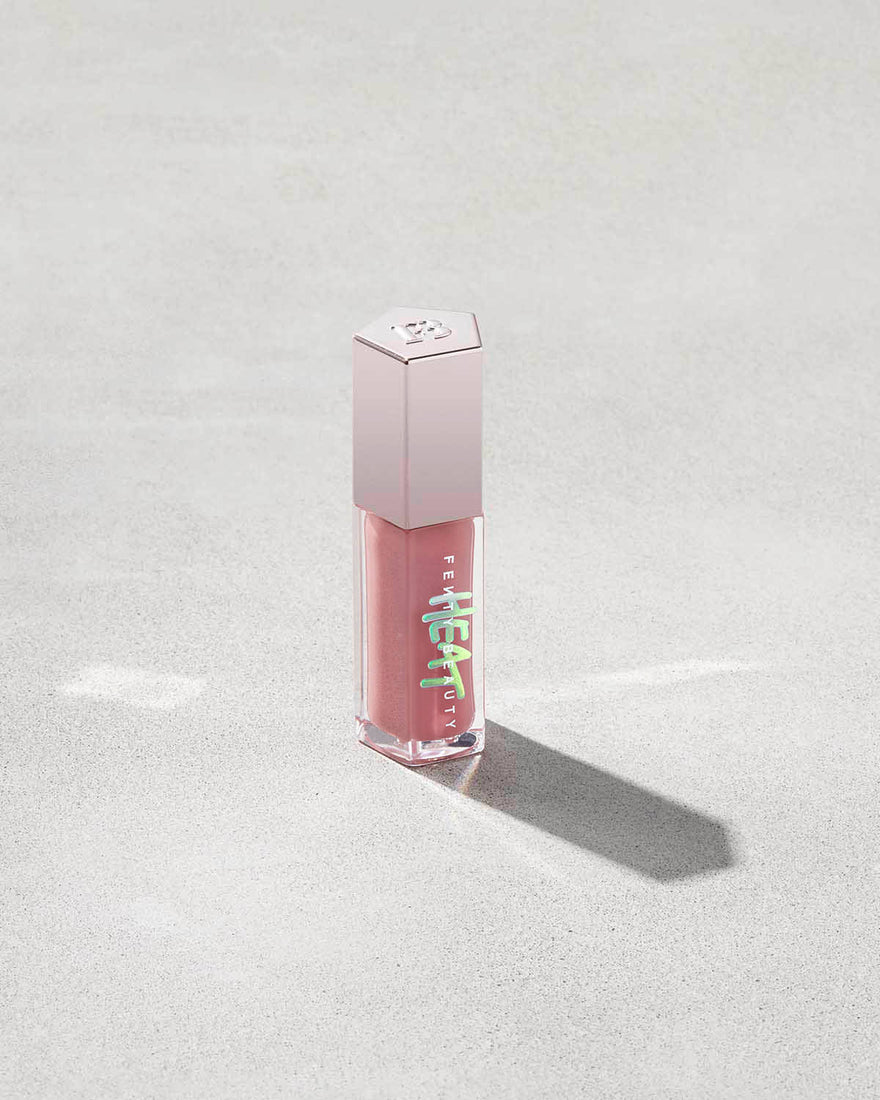 tube of Fenty Beauty Gloss Bomb Heat Universal Lip Luminizer + Plumper in shade Fussy Heat on concrete background