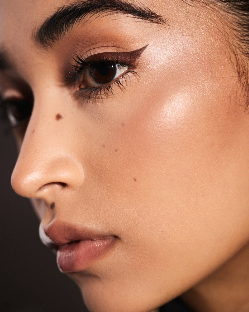 model with winged eyeliner look using Fenty Beauty Flyliner Longwear Liquid Eyeliner in shade In Big Truffle