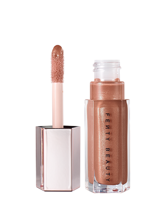A closed tube of Gloss Bomb Universal Lip Luminizer in the shade Fenty Glow on a grey background. A closed tube of Gloss Bomb Universal Lip Luminizer in the shade Fenty Glow on a grey background.