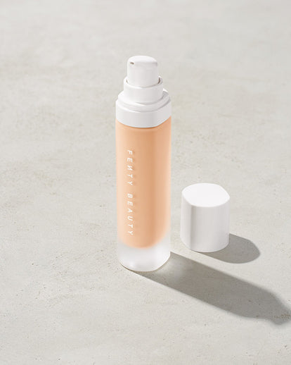open bottle of Fenty Beauty Pro Filt'r Soft Matte Longwear Foundation with pump dispenser in shade #100 on concrete background