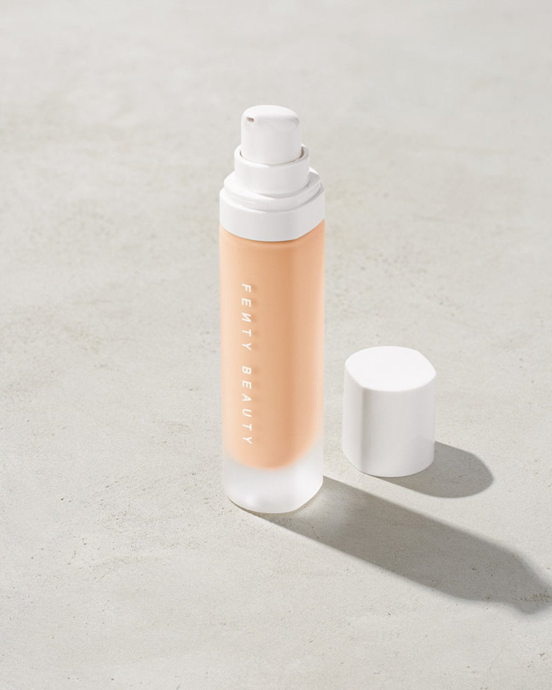 open bottle of Fenty Beauty Pro Filt'r Soft Matte Longwear Foundation with pump dispenser in shade #100 on concrete background