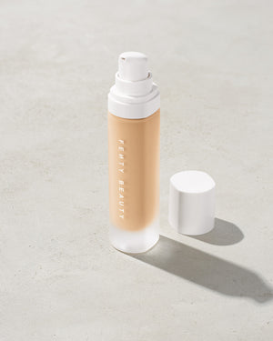 open bottle of Fenty Beauty Pro Filt'r Soft Matte Longwear Foundation with pump dispenser in shade #150 on concrete background