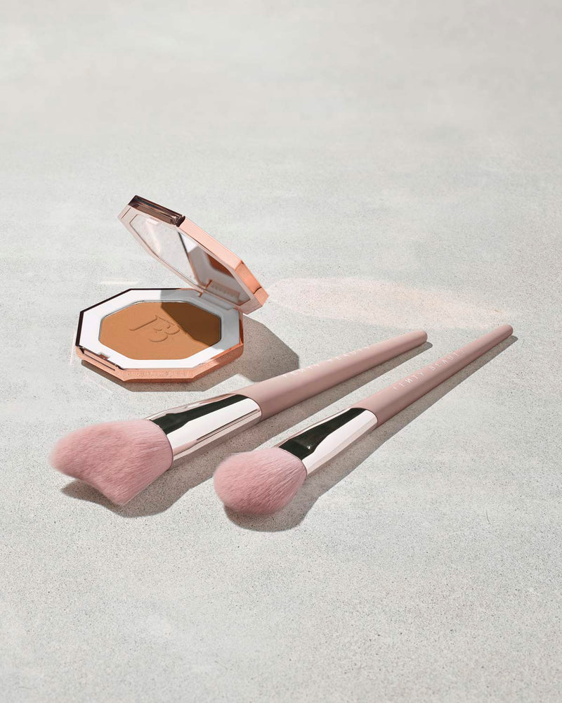 Sun Stalk'r Instant Warmth Bronzer with two light pink face brushes next to the open product