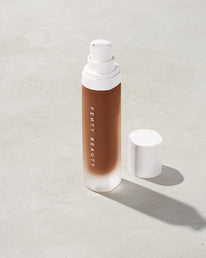open bottle of Fenty Beauty Pro Filt'r Soft Matte Longwear Foundation with pump dispenser in shade 470 on concrete background