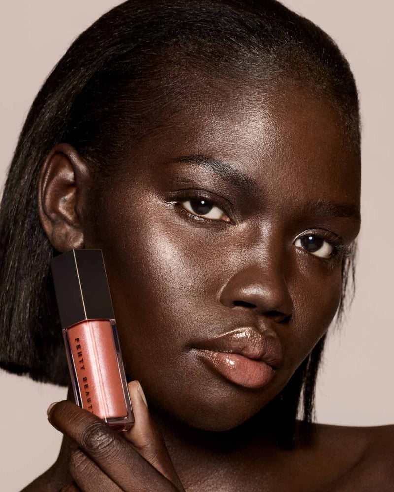 deep skin toned model wearing gloss bomb universal lip luminizer in Fenty Glow