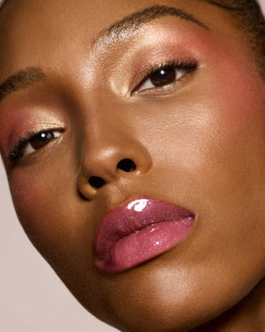 deep skin toned model wearing gloss bomb universal lip luminizer in shade RiRi