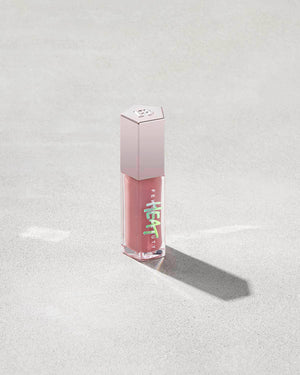 tube of Fenty Beauty Gloss Bomb Heat Universal Lip Luminizer + Plumper in shade Fussy Heat on concrete background