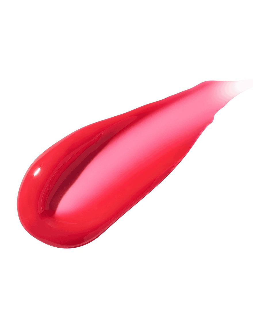 A smear of Gloss Bomb Heat lip gloss in the shade Hot Cherry on a white background.