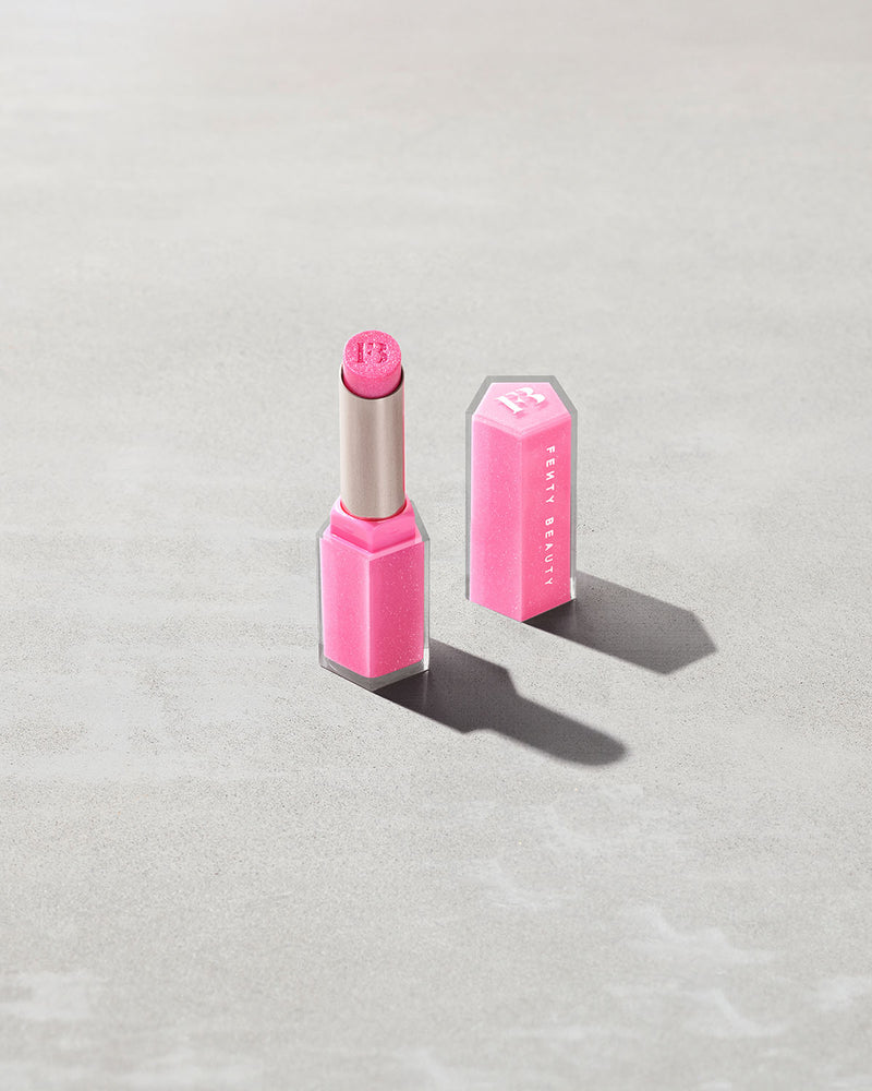 Open product shot of Gloss Bomb Stix Shimmer in shade Flamingo Fling on a concrete background.