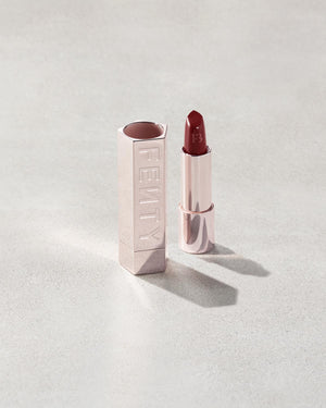 Fenty Icon lipstick shade in Board Memb'r, next to a metallic lipstick case.
