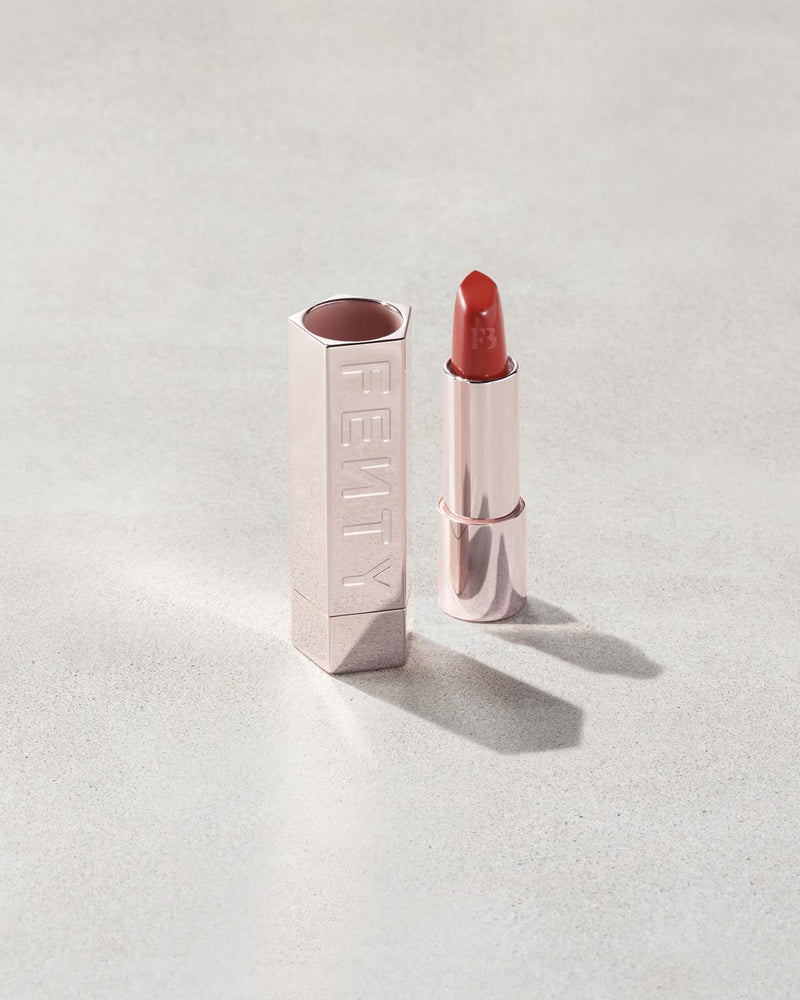 Fenty Icon lipstick shade in Grill Mast'r, next to a metallic lipstick case.
