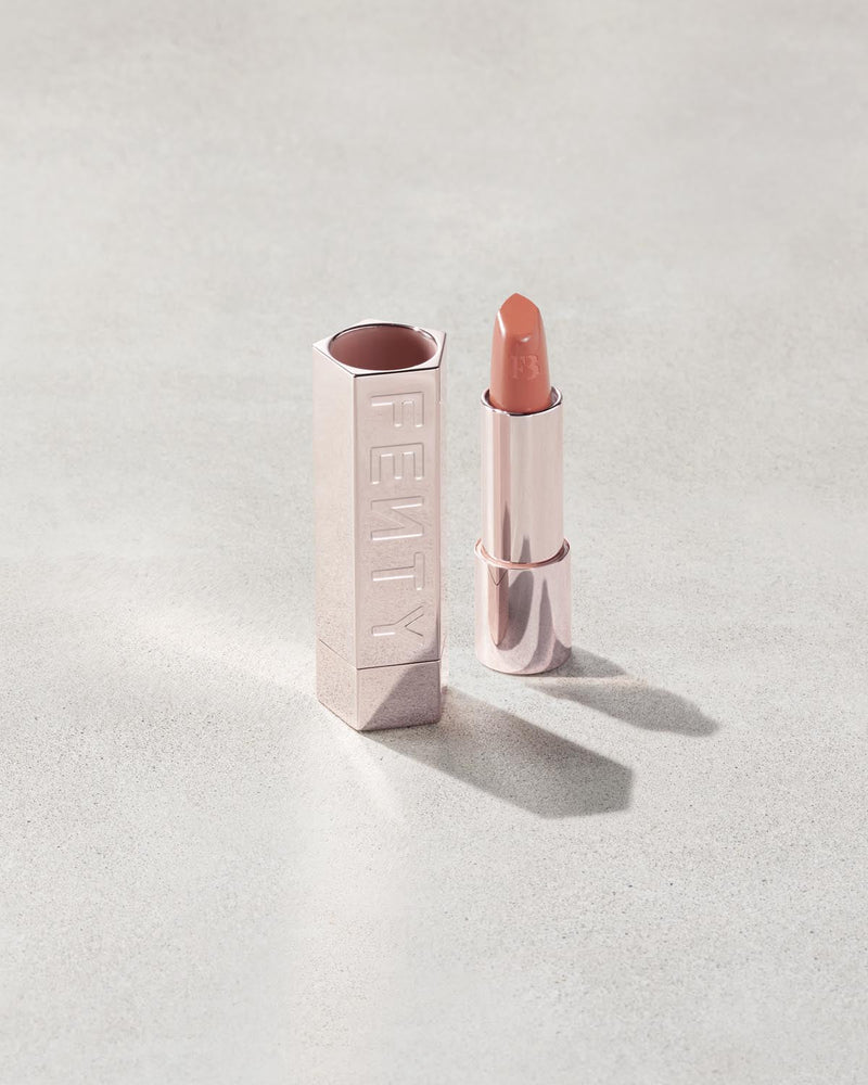 Fenty Icon lipstick shade in Pose Queen, next to a metallic lipstick case.