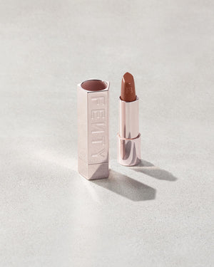 Fenty Icon lipstick shade in She a CEO, next to a metallic lipstick case.